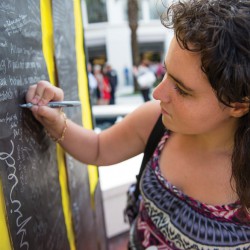 A student leaves a message to those affected by 9/11 on a poster resembling the twin towers.
