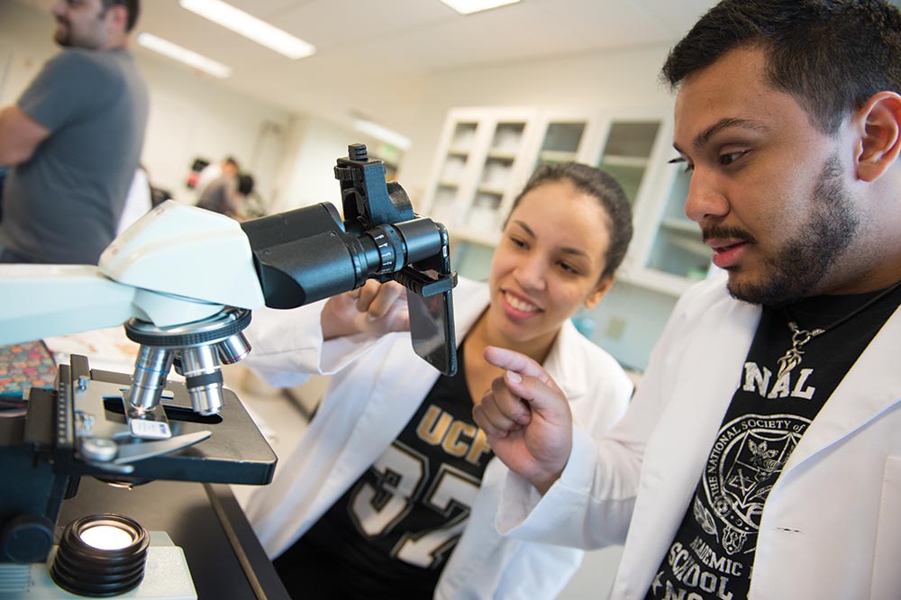 Biology students test a 3-D printed smartphone-to-microscope attachment created by Valencia student Josue Gimbernard. Right: Elizabeth Treat tests her 3-D printed cookbook holder.