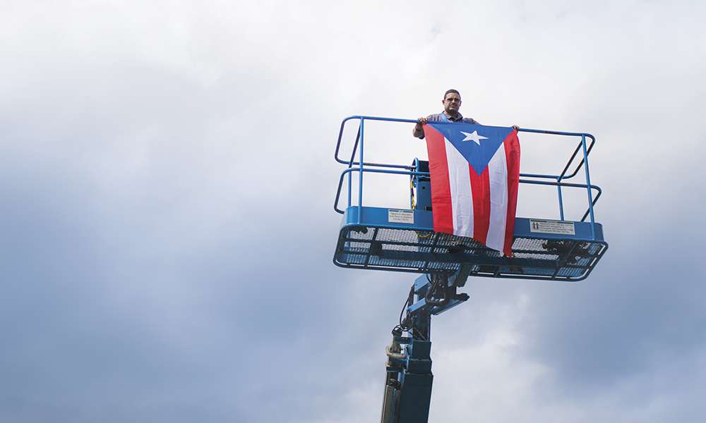 #FuerzaPuertoRico: Following the aerial peace sign photoshoot, a member of the East Campus grounds crew member raises the Puerto Rican flag in support of the U.S. territory left reeling by Hurricane Maria.