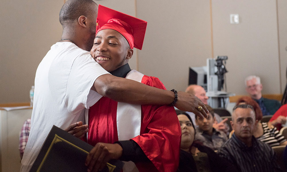 YouthBuild graduate Quran Shabazz earns a hug from a family member