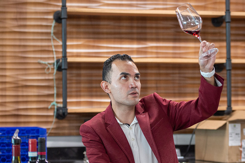 Luis Romero, sommelier, gently swirls wine in a glass—taking note of the body and density of it.
